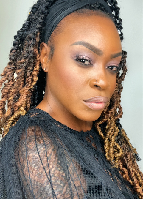 Model with dreadlocks, hair pulled back and full makeup looking at camera